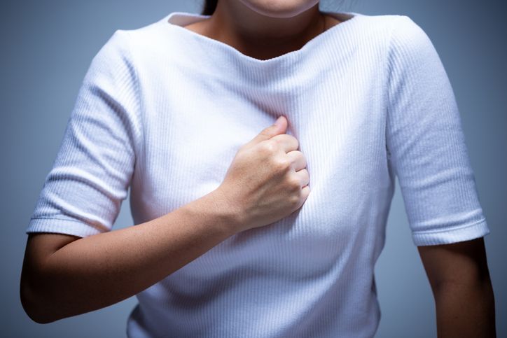 Midsection Of Woman Touching Chest In Pain While Standing Against Gray Background