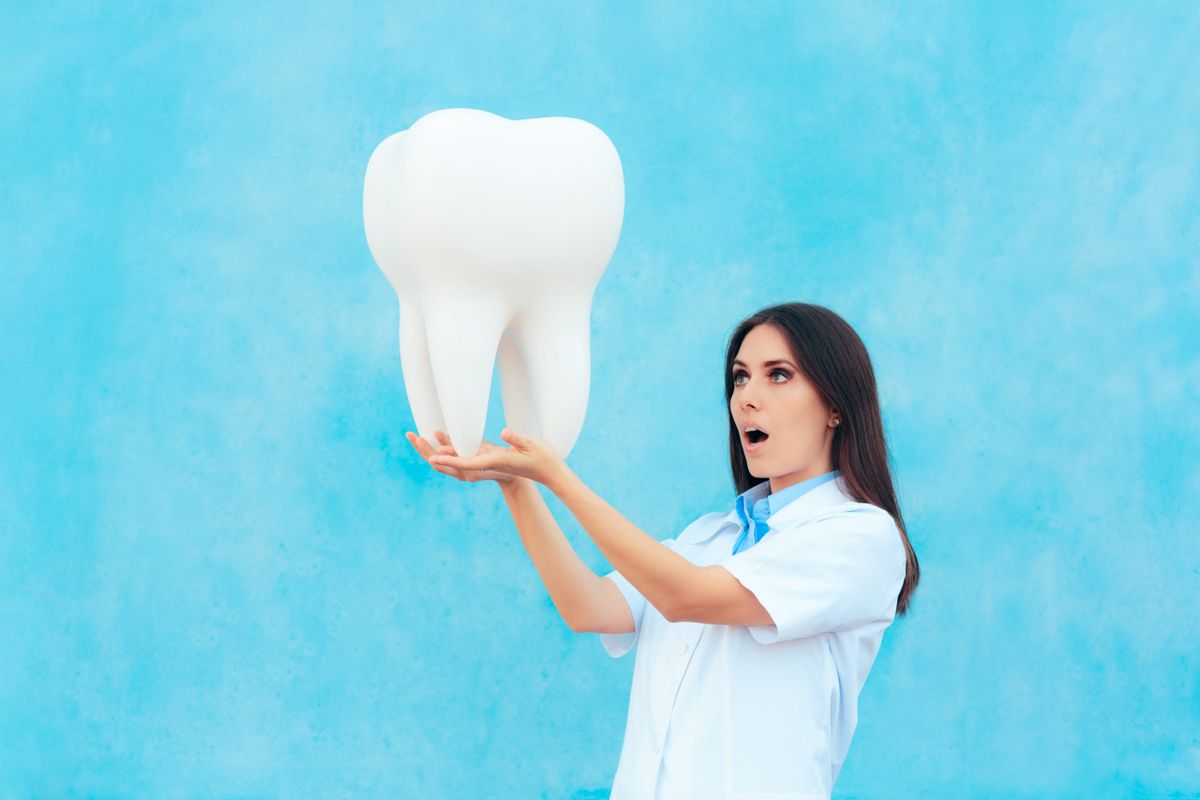 Female,Dentist,In,White,Coat,With,Big,Molar,Tooth,Model.