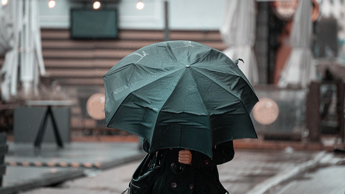 Woman,Walking,In,The,City,With,Green,Umbrella,On,Rainy