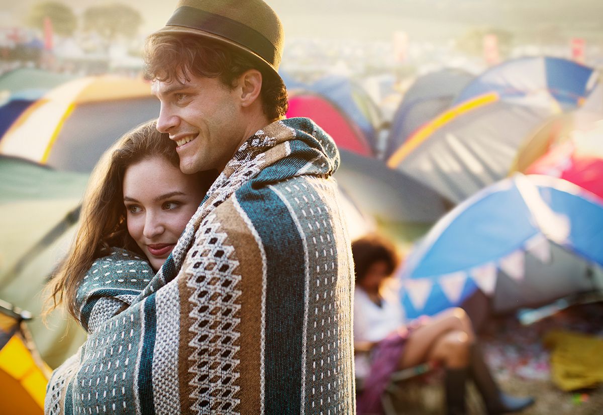 Couple,Wrapped,In,A,Blanket,Outside,Tents,At,Music,Festival
