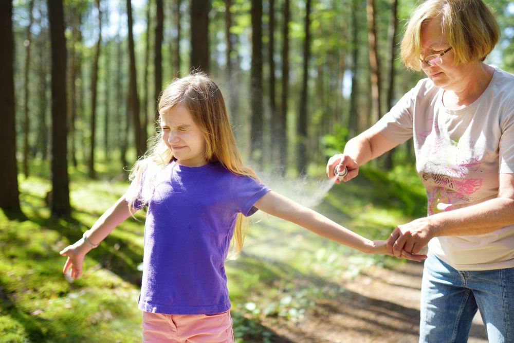 Middle,Age,Woman,Applying,Insect,Repellent,To,Her,Granddaughter,Before