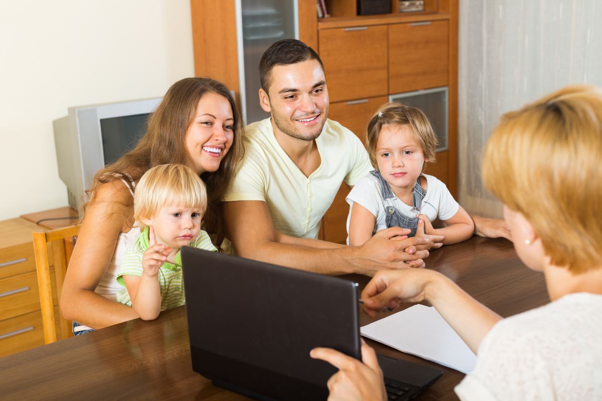 Smiling,Young,Parents,And,Two,Daughters,Sitting,In,Front,Of