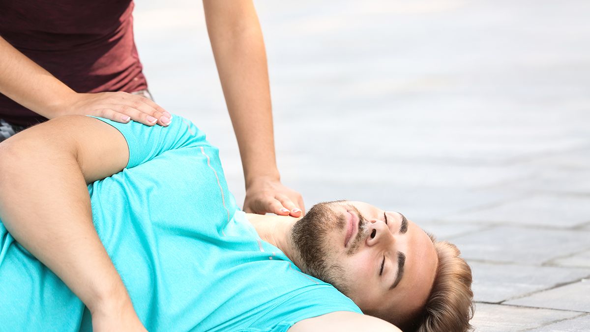 Woman,Checking,Pulse,Of,Unconscious,Man,Outdoors