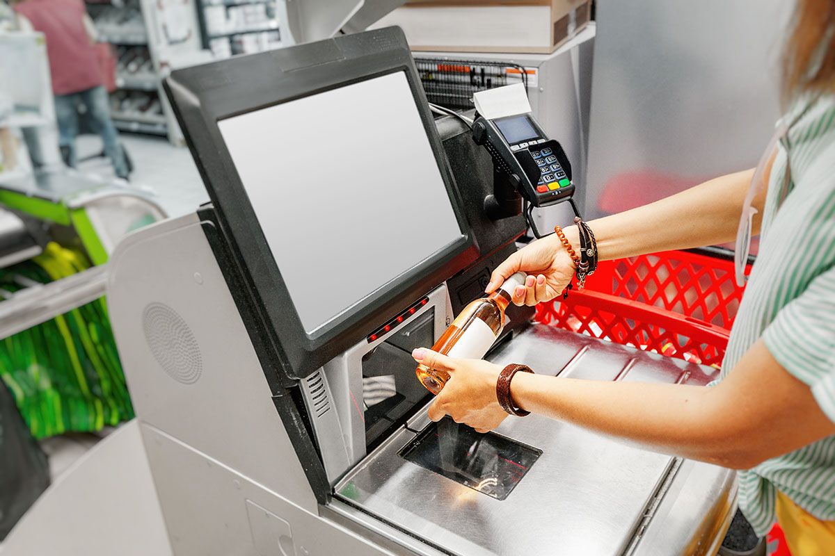 Girl,Customer,Scans,Bottle,Of,Wine,At,The,Self-service,Checkout