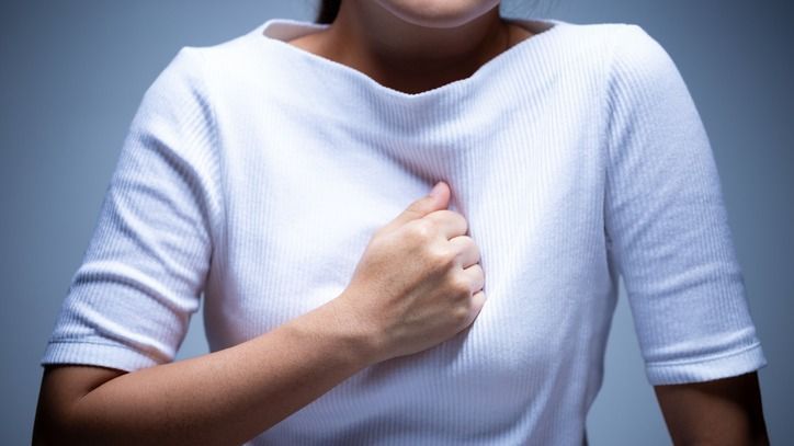 Midsection Of Woman Touching Chest In Pain While Standing Against Gray Background