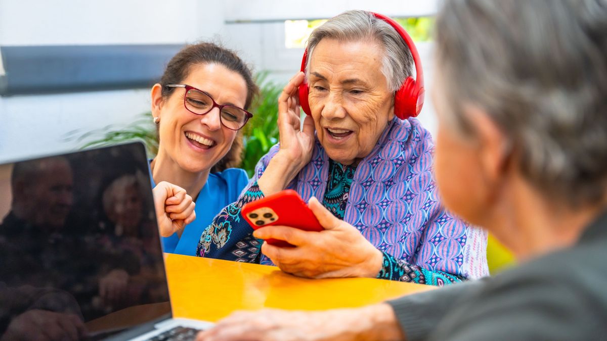 Senior,Woman,Assisted,By,Caregiver,Having,Fun,Listening,To,Music