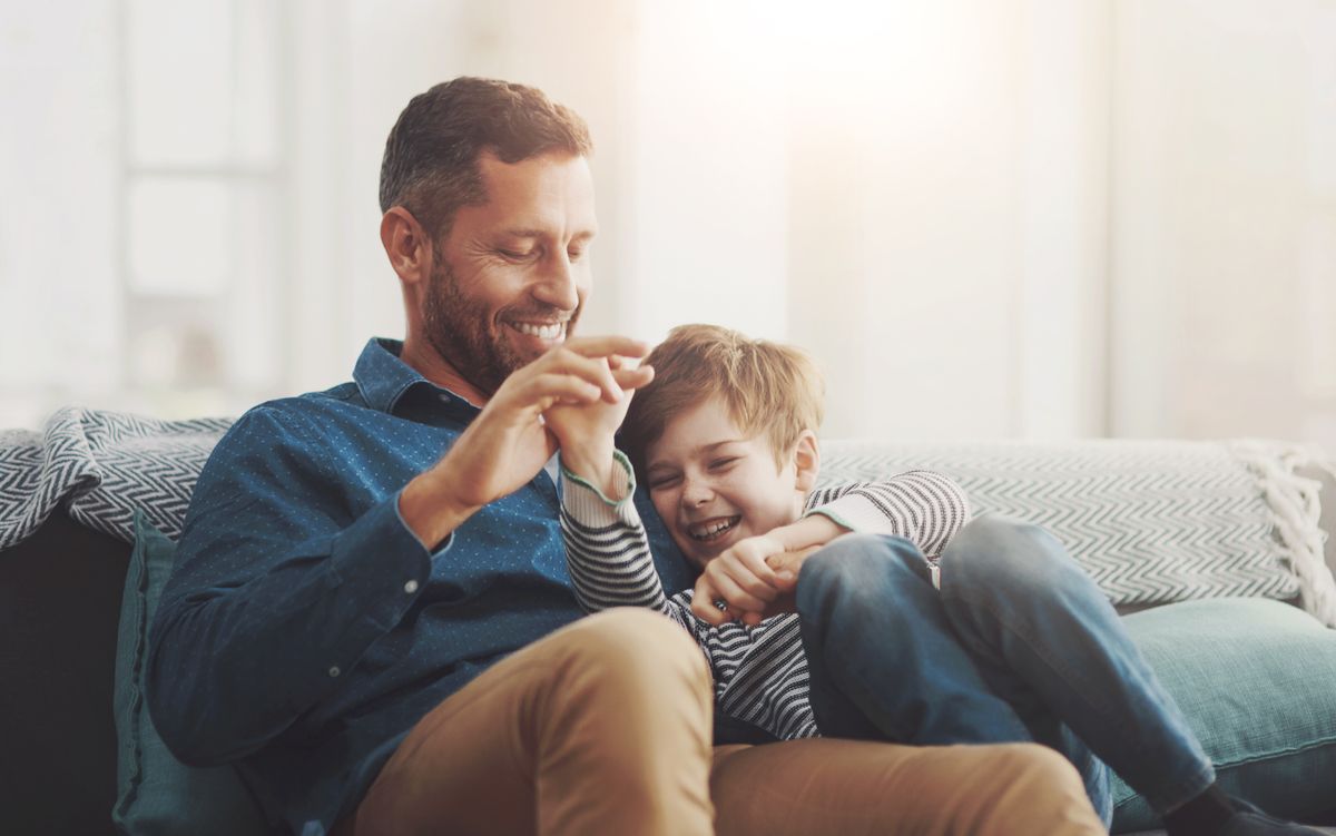 Father,,Boy,And,Laughing,On,Sofa,Together,In,Home,,Bonding