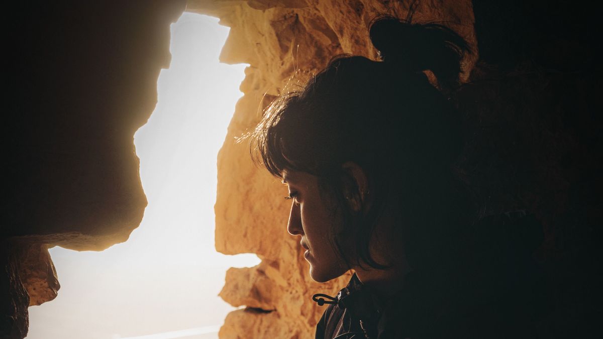 woman in black jacket sitting on rock formation during daytime