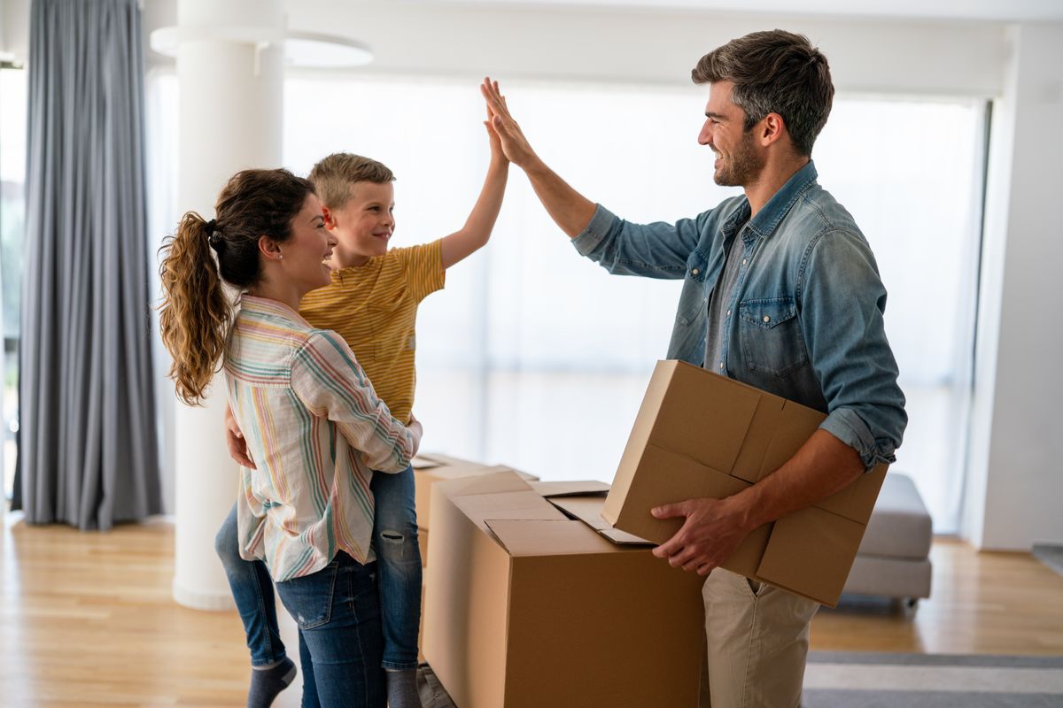 Happy,Family,With,Cardboard,Boxes,In,New,House,At,Moving