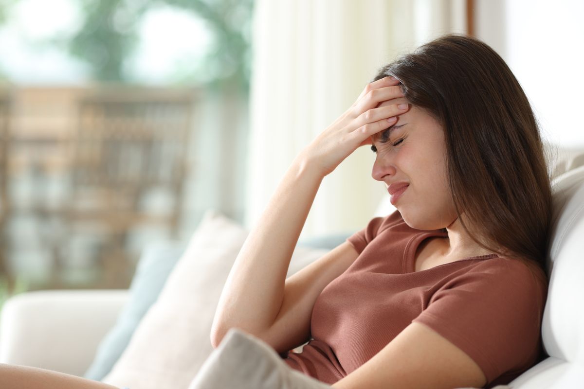 Woman,In,A,House,Suffering,Head,Ache,Sitting,On,A